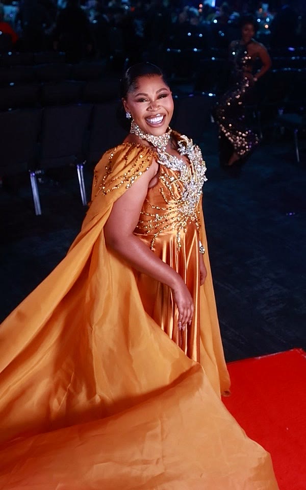 Guest in a gold caped gown on the GlamBot® red carpet